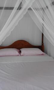 a white bed with a wooden headboard and pillows at Coco One Holiday Inn in Mirissa