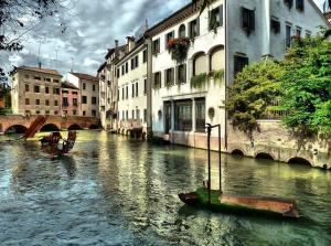 a boat on a river in a city with buildings at Holiday Treviso Suite LOMBARDI in Treviso