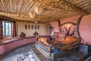 ein Schlafzimmer mit einem großen Holzbett in einem Zimmer in der Unterkunft Rhino Watch Safarilodge in Mweiga