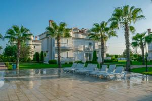 un grupo de sillas y palmeras frente a un edificio en Belek Golf Village - Villa with shared pool, en Belek