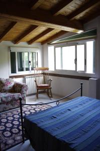 a bedroom with a bed and a chair and windows at Ca' di Croso' in Riccò del Golfo di Spezia