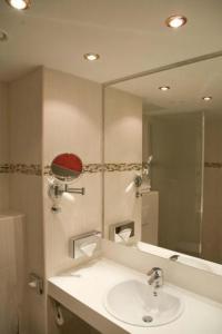 a bathroom with a sink and a large mirror at Grand Hotel Dream Main City Center in Frankfurt/Main