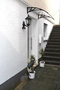 un edificio bianco con due piante in vaso accanto a una porta di 2x Monteurwohnung 1x 2 kleine Einzelzimmer 1x Doppelbett und Schlafcouch im Wohnbereich a Siegen
