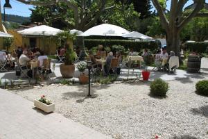 eine Gruppe von Menschen, die an Tischen unter Sonnenschirmen sitzen in der Unterkunft Jac'Soul Restaurant & Chambres d'hotes in Sablet