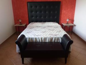 un letto nero in una stanza con due tavolini di Pergole a Realmonte