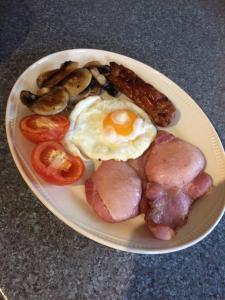 a plate of breakfast food with eggs meat and mushrooms at Jonti Bed And Breakfast in Corfe Castle