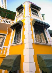 un edificio giallo con due finestre e ombrelloni di Hotel Vila 1928 a Tirana
