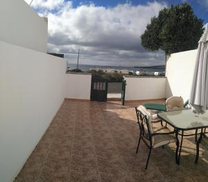 un patio con mesa, sillas y una pared blanca en Apartamento Ayla, en Playa Quemada