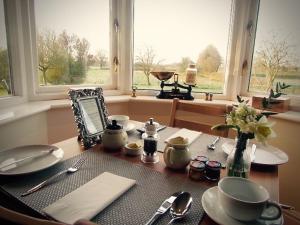 a table with plates and utensils in front of a window at The Moorhead Bed & Breakfast in Wem
