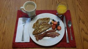 a plate with bacon and toast and a cup of coffee at Carriage House Inn Four and a Half Stars in Grand Falls