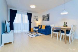 a living room with a table and a blue couch at Apartament Darłówko in Darlowko