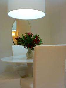 un jarrón de flores sobre una mesa con un espejo en Il Borgo Appartamenti by KasaVacanze, en Porto San Paolo