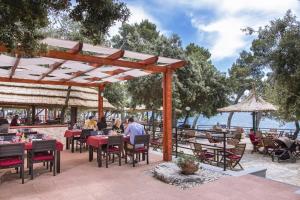 a restaurant with tables and chairs and a view of the water at Mobile Homes Crystal Camp Soline in Biograd na Moru