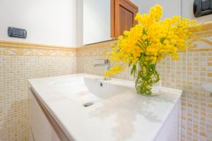 a bathroom with a vase of yellow flowers on a sink at B&B BOUTIQUE DI CHARME "ETNA-RELAX-NATURA" in Zafferana Etnea +95 photos