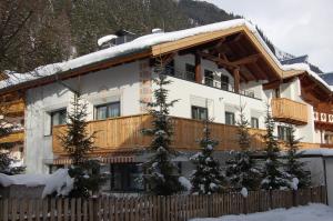 ein Gebäude mit einem Holzzaun im Schnee in der Unterkunft Apart Ingrid in Ischgl