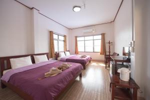 een slaapkamer met 2 bedden, een bureau en 2 ramen bij Mountain View House in Sangkhla Buri