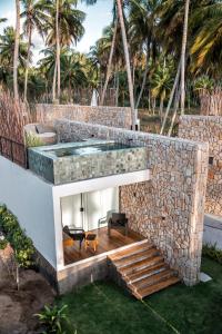 a swimming pool in a stone wall with a bench and chairs at Pedras Do Patacho Hotel Boutique Experience in Pôrto de Pedras