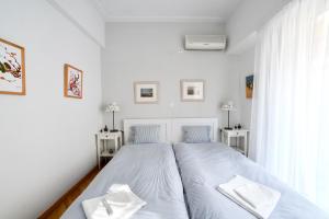 a white bedroom with two beds and a window at Athens Squared Apartments in Athens