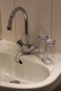 um lavatório com uma torneira e dois copos em Erve de Bosch em Benteloo