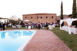 a group of people standing around a pool at a wedding at Le Checche in Pienza