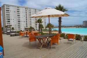 a table and chairs with an umbrella next to a pool at Laguna Bahía, Algarrobo in Algarrobo