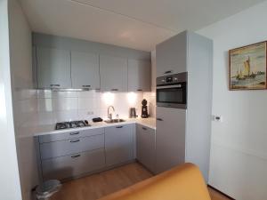 a kitchen with white cabinets and a stove top oven at BRANDING Bed by the Sea in Westkapelle