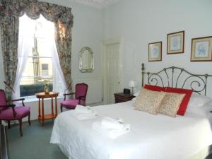 a bedroom with a bed and two chairs and a window at Brocks in Bath
