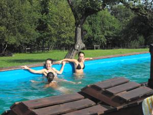 three people in a swimming pool with a tree at Agroturystyka Zacisze Czarna Owca in Brzeżanka