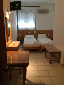 een kamer met 3 bedden, een tafel en een raam bij Hotel Christina in Skiathos-stad