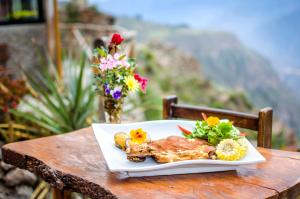 a plate of food on a table with a view at La Granja del Colca in Cabanaconde