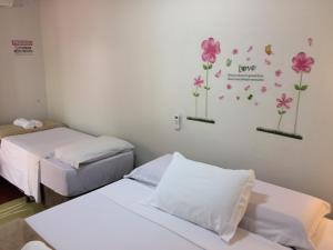 two beds in a room with flowers on the wall at Pousada Flor de Debora in Alto Paraíso de Goiás