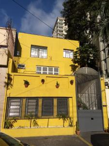 un edificio amarillo con plantas delante de él en Hospedaria Cambuci Unidade Ipiranga, en São Paulo