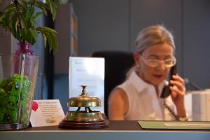 een vrouw die aan een tafel zit te praten op een mobiele telefoon bij Pension Vicus in Passau