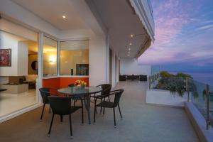 Un comedor con mesa y sillas en un balcón. en Antiopi Luxury Villa, en Agia Pelagia