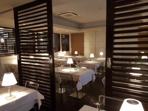 ステッツァーノにあるメルキュール ベルガモ アエロポルトの白いテーブルと椅子、照明が備わるレストラン