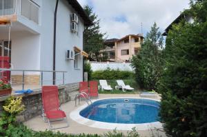 a swimming pool with red chairs next to a house at Villa Holiday in Balchik