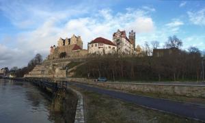 un château au sommet d'une colline à côté d'une rivière dans l'établissement Zimmervermietung Barth, à Bernburg