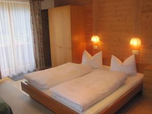 Schlafzimmer mit einem Bett mit weißer Bettwäsche und Kissen in der Unterkunft Galzigblick in Pettneu am Arlberg