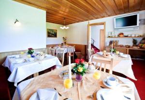 uma sala de jantar com mesas e cadeiras brancas e uma televisão em Pension Ederhof em Jochberg
