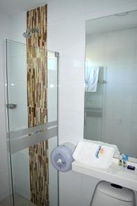 a bathroom with a toilet and a glass shower at Sol Caribe Hotel in Soledad