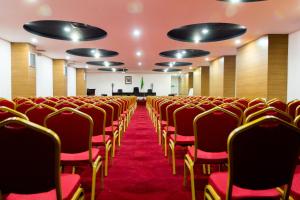 an empty conference room with red chairs and a podium at Complexe Touristique BouZour in Mostaganem