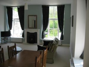 a living room with a table and chairs and windows at Litton Mill Apartment in Tideswell