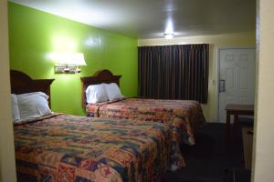 Habitación de hotel con 2 camas y paredes verdes en Claremore Motor Inn en Claremore