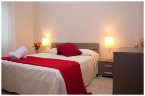 1 dormitorio con 1 cama con manta roja y 2 lámparas en Appartamenti Sant' Andrea, en Trapani