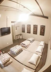 a room with three beds with pillows and a tv at Feb hostel in Tainan