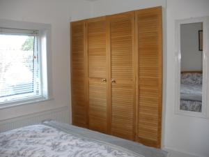 a bedroom with a wooden closet and a bed at Trent Cottage in Newark upon Trent