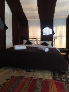 Un dormitorio con una cama grande con almohadas. en Bivouac Les Clés de Desert, en Adrouine