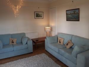 a living room with two blue couches and a table at Auchencairn Cottage in Brora