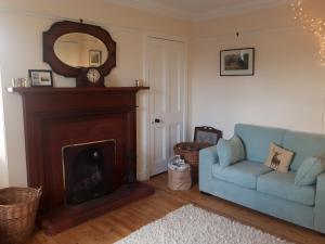 a living room with a fireplace and a blue couch at Auchencairn Cottage in Brora