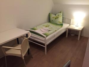 ノイブランデンブルクにあるPension ,,Vier Tore''のベッド、テーブル、デスクが備わる小さな客室です。